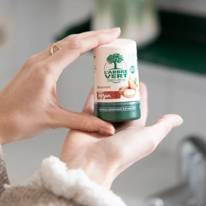 Deux mains tenant un flacon de déodorant L'Arbre Vert bien-être au parfum Argan de 50 ml.